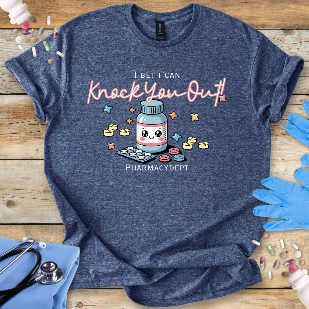 Heather Navy t-shirt with a pharmacy-themed graphic and 'I bet I can knock you out' text on a wooden surface with medical accessories.