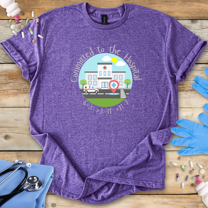Purple t-shirt with a hospital-themed graphic and 'Committed To The Hospital' on a wooden surface with medical supplies.