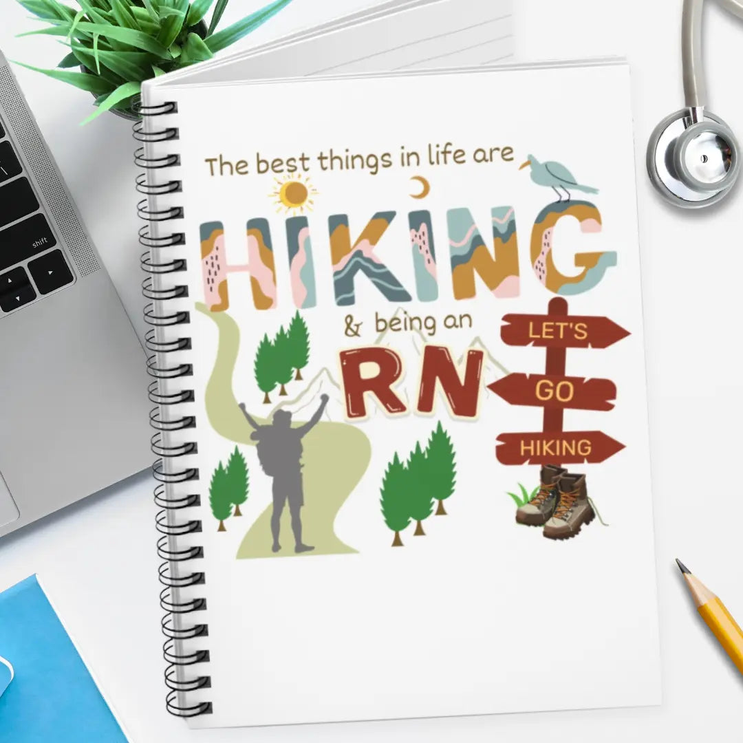 Notebook with hiking and RN illustration on a desk with laptop and stethoscope.