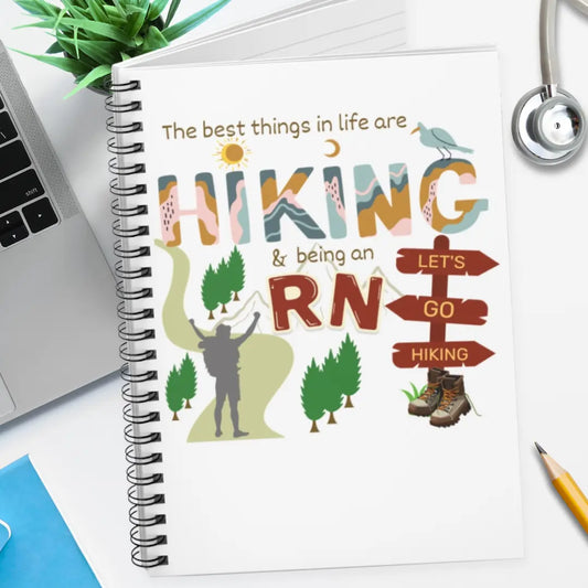Notebook with hiking and RN illustration on a desk with laptop and stethoscope.