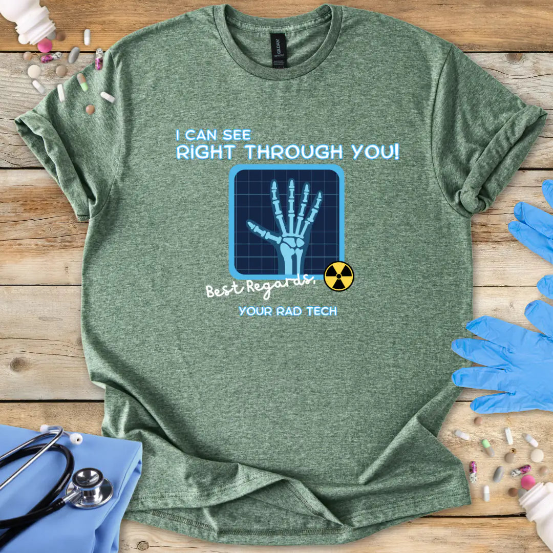 Heather military green t-shirt with medical-radiology themed graphic and 'I can see right through you' text on a wooden surface with medical gloves.