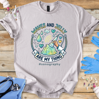 Gray t-shirt with 'Waves and Jelly are my thing #sonography' design on a wooden surface with medical tools.