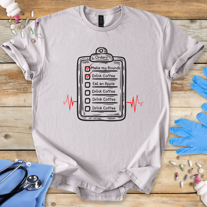 Gray med t-shirt with a medical doctor graphic on a wooden surface with medical accessories.