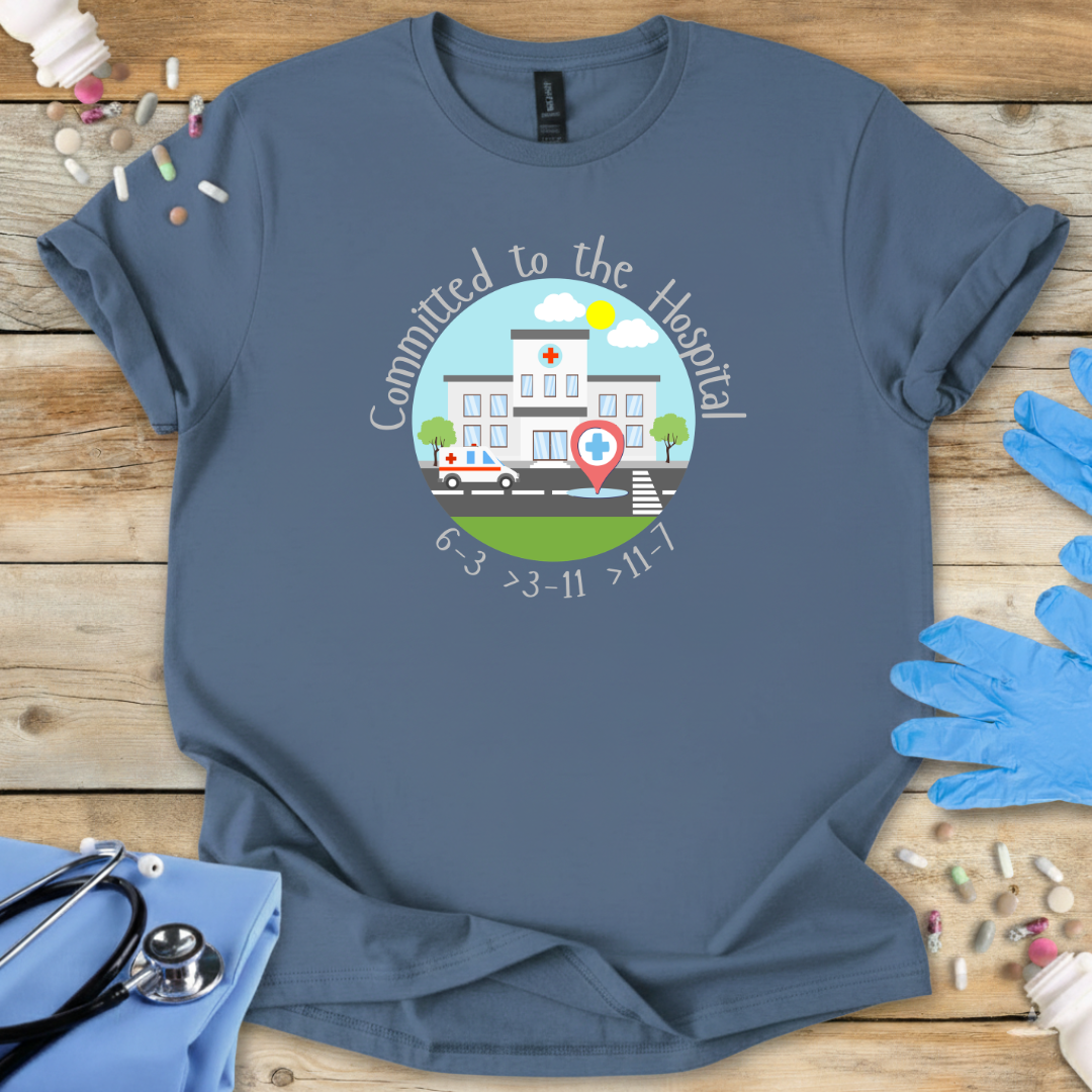 Indigo blue t-shirt with a hospital-themed graphic and 'Committed To The Hospital' on a wooden surface with medical supplies.
