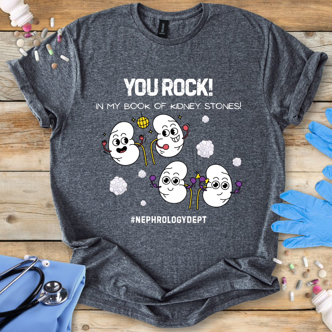 Dark Heather Grey t-shirt with cartoon kidneys and 'You rock in my book of kidney stones, nephrology dept.' text on a wooden surface with medical accessories.