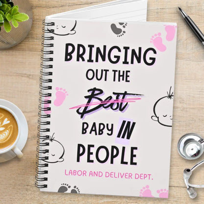 Obstetrics notebook with 'Bringing Out The Baby In People' quote on a wooden surface with coffee and stethoscope.