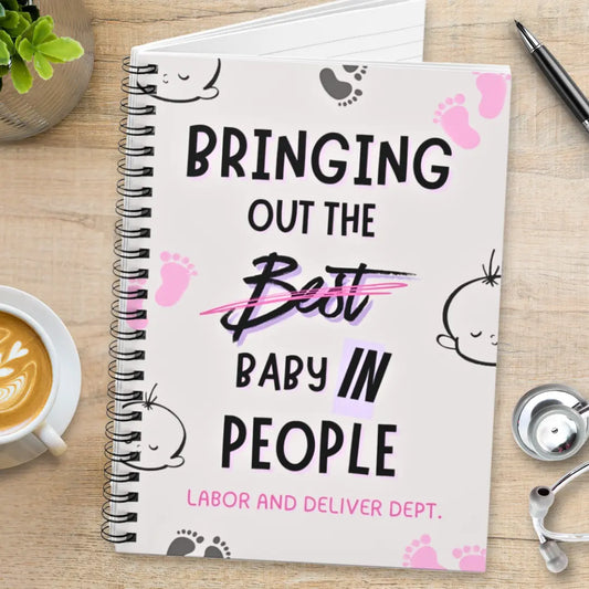 Obstetrics notebook with 'Bringing Out The Baby In People' quote on a wooden surface with coffee and stethoscope.
