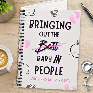 Obstetrics notebook with 'Bringing Out The Baby In People' quote on a wooden surface with coffee and stethoscope.