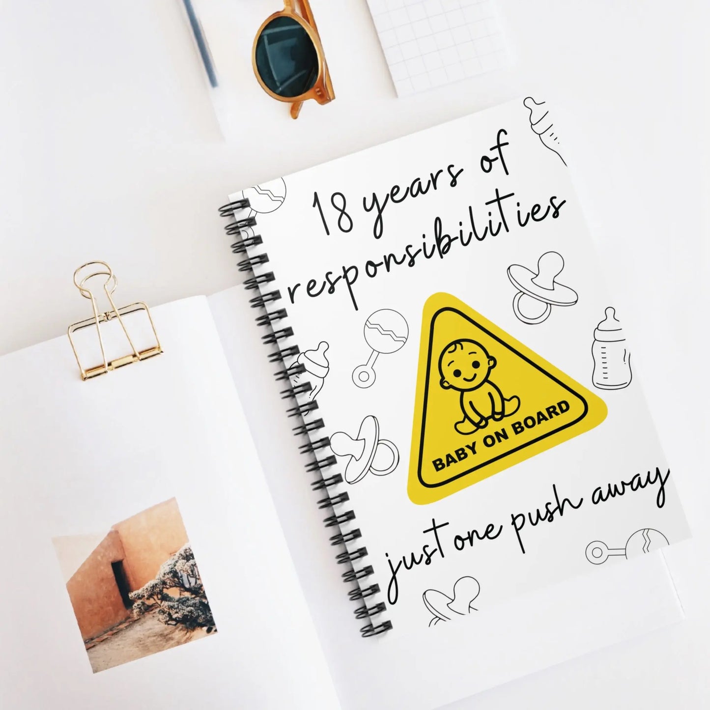 Notebook with '18 years of responsibilities' logo and baby-themed graphics on a white background