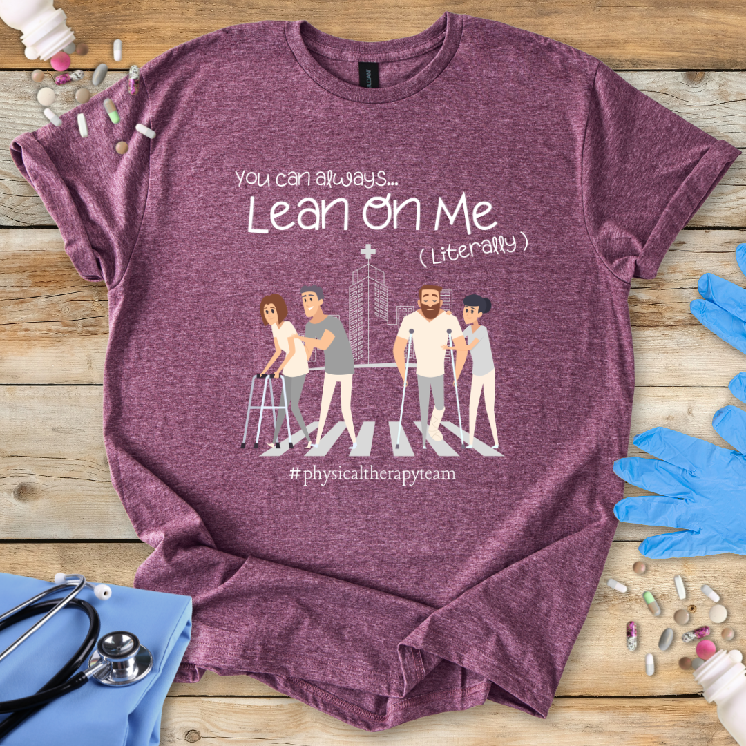 Maroon med t-shirt with graphic design and 'Physical Therapy Team' text on a wooden surface with medical accessories.