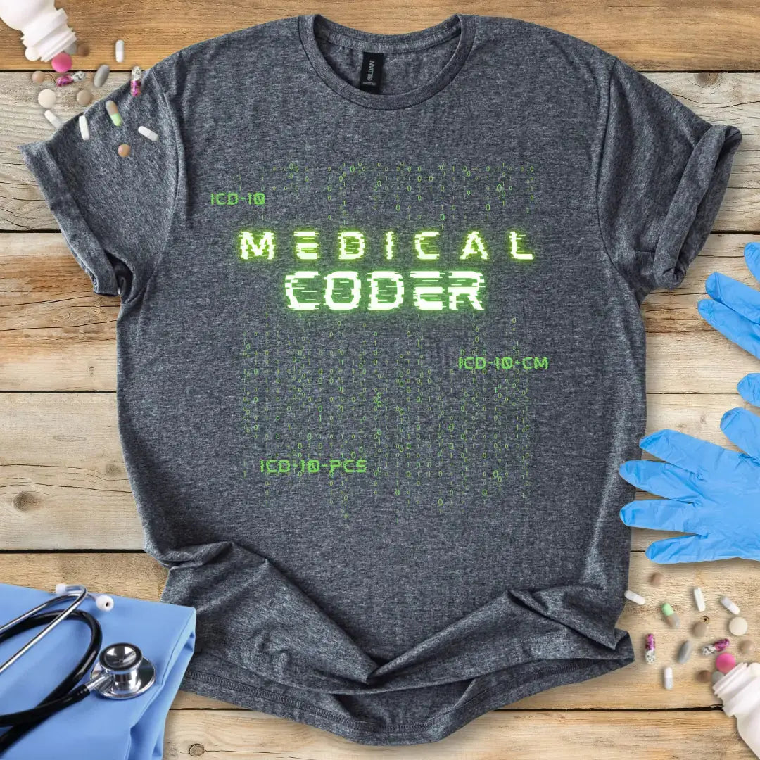Gray t-shirt with 'Medical Coder' text on a wooden surface with medical items.