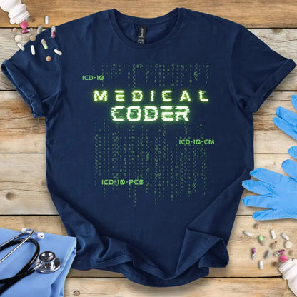 Navy blue t-shirt with 'Medical Coder' text on a wooden surface with medical items.