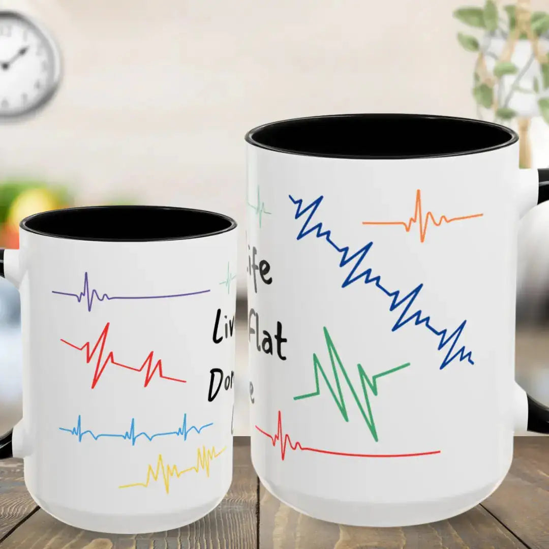 Two white mugs with colorful heartbeat lines and text on a wooden surface.