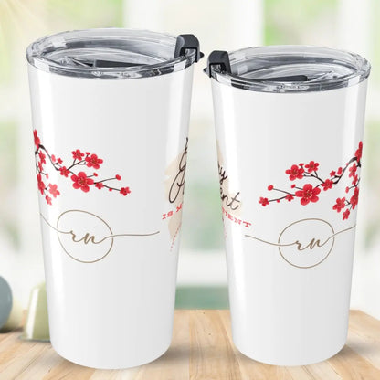 Two white tumblers with cherry blossom design and 'RN' text on a wooden surface.