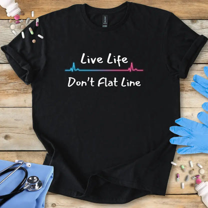 Black t-shirt with 'Live Life Don't Flat Line' text on a wooden surface with medical accessories.