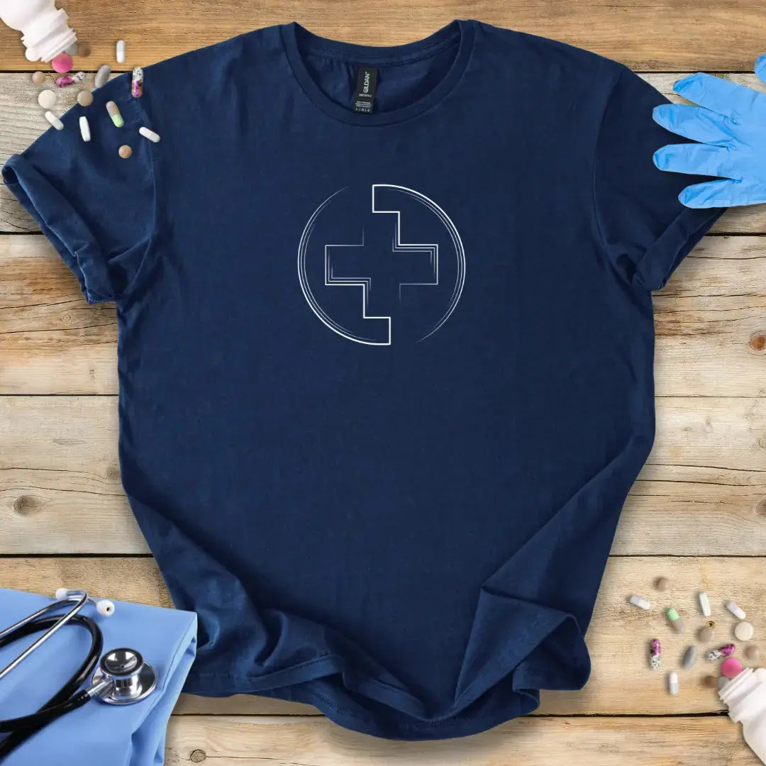 Navy blue t-shirt with a white medical logo symbol on a wooden surface with medical supplies.