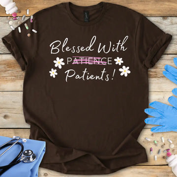 Brown t-shirt with 'Blessed With Patients Not Patience!' text on a wooden surface with medical items.