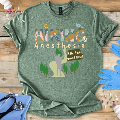 Green t-shirt with 'Hiking & Anesthesia Oh the good life!' design on a wooden surface with medical supplies.