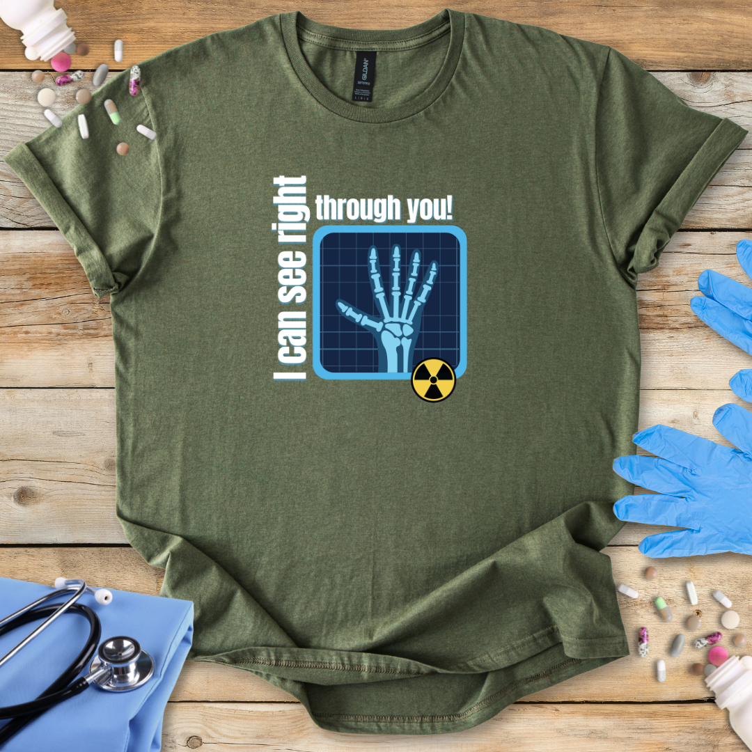 Military Green med t-shirt with x-ray design and 'I can see right through you' text on a wooden surface with medical accessories.