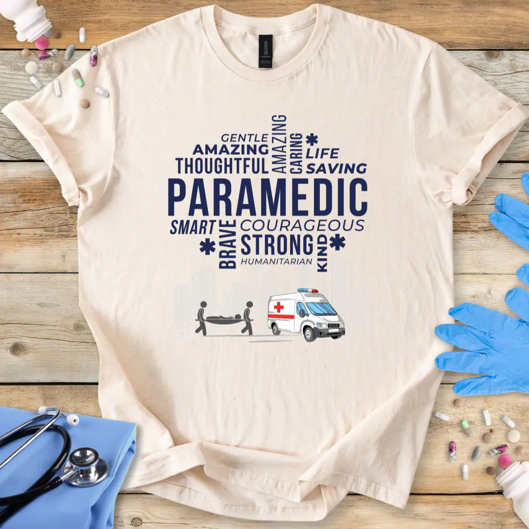 Beige t-shirt with paramedic-themed text and graphics on a wooden surface with gloves and stethoscope.