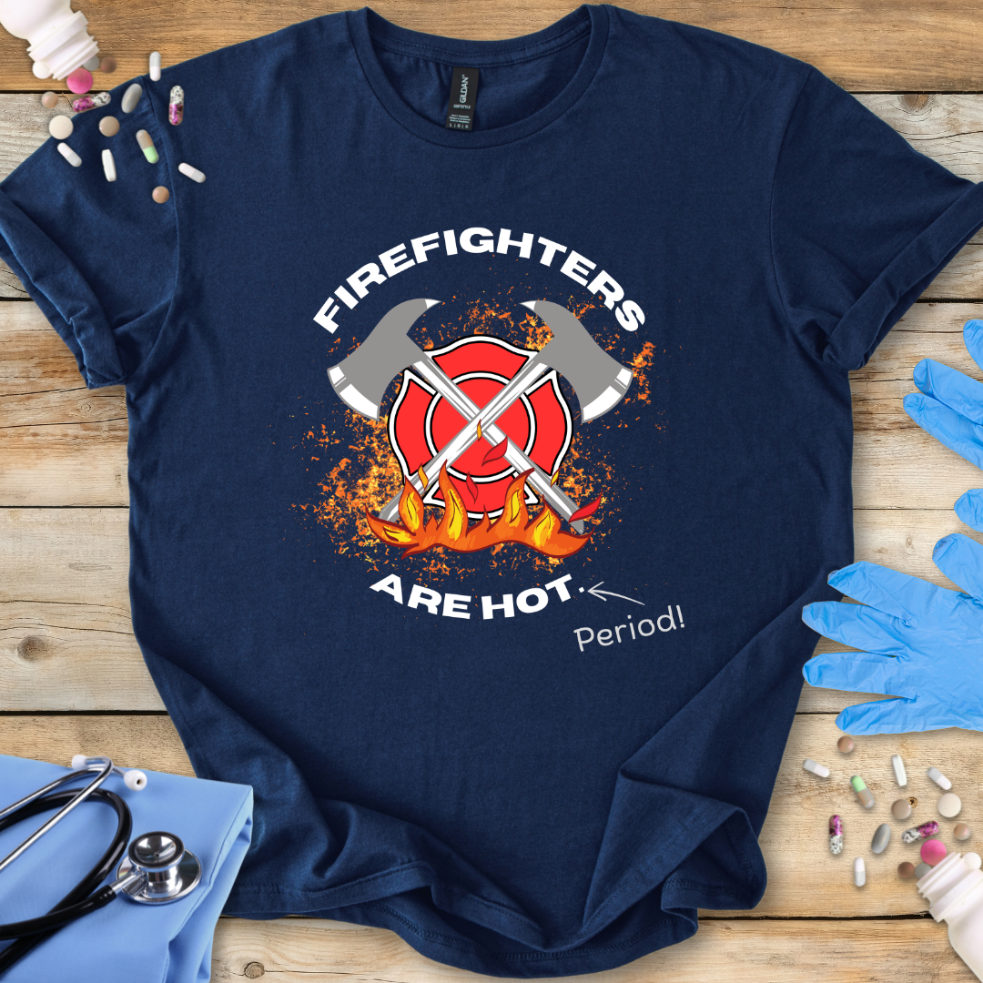 Navy blue t-shirt with 'Firefighters Are Hot Period!' graphic on a wooden surface with medical supplies.