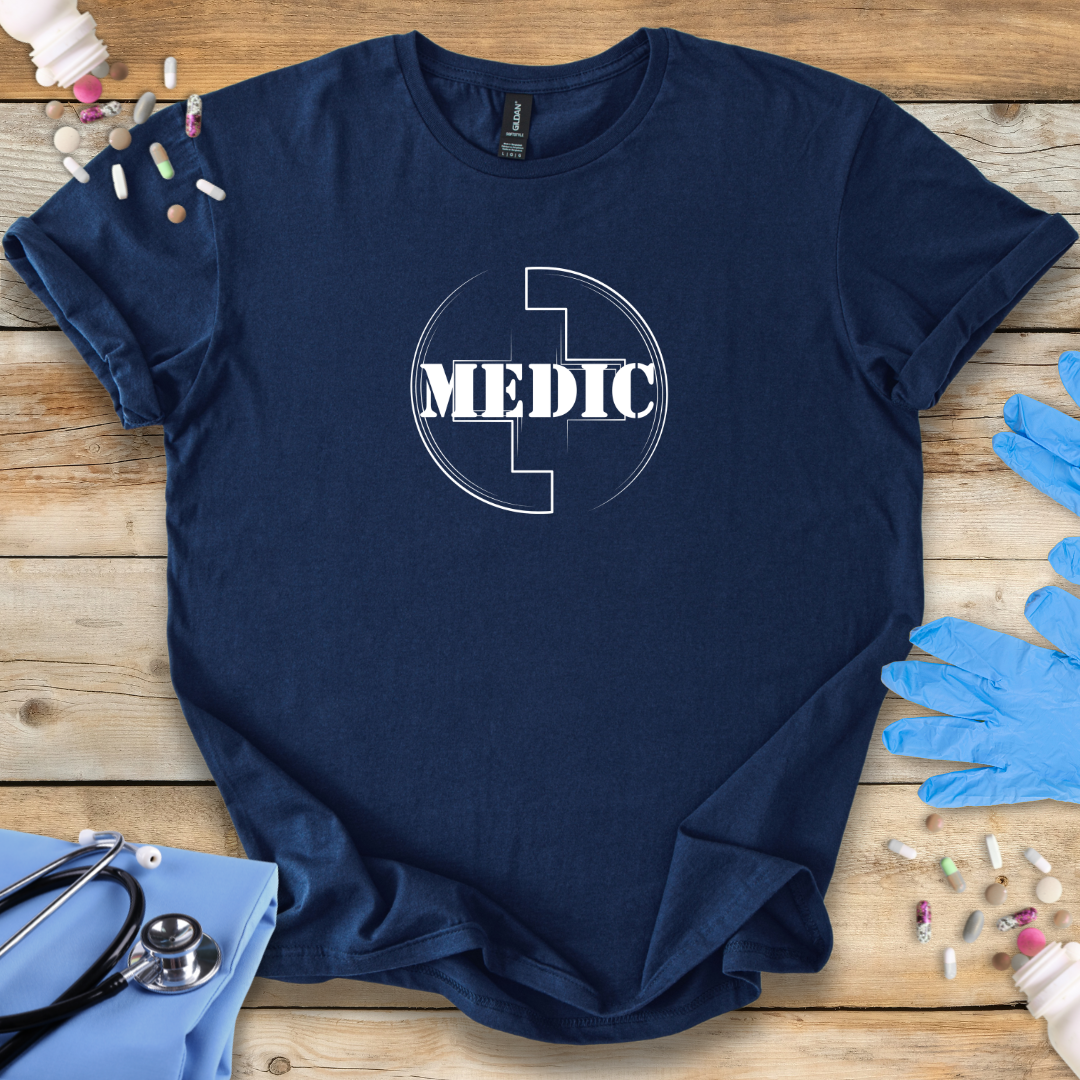 Navy blue t-shirt with 'MEDIC' design on a wooden surface with medical supplies.