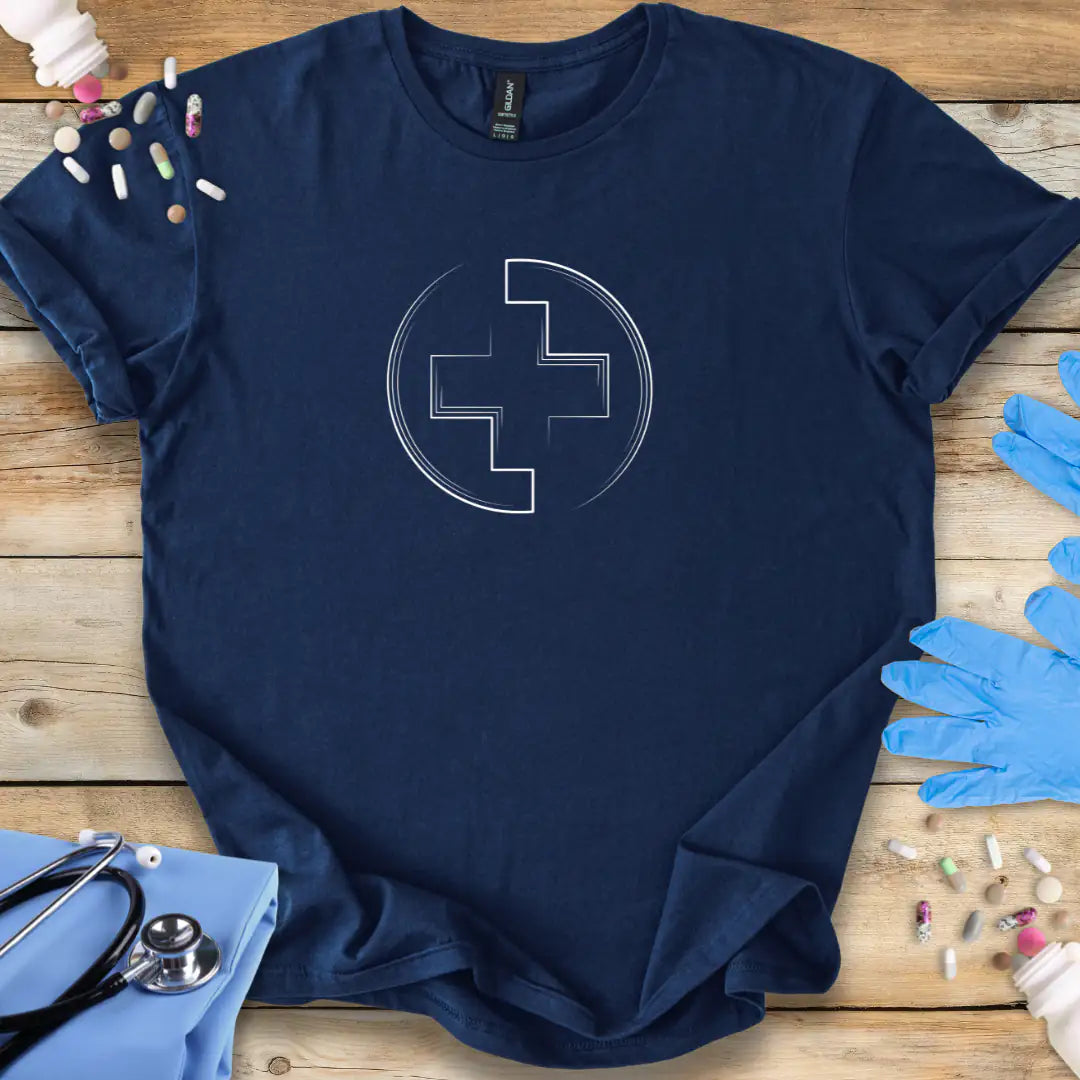 Navy blue t-shirt with a white cross medical logo on a wooden surface with medical items.
