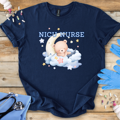 Navy blue t-shirt with 'NICU Nurse' text featuring a bear on a cloud and moon, placed on a wooden surface with medical accessories.