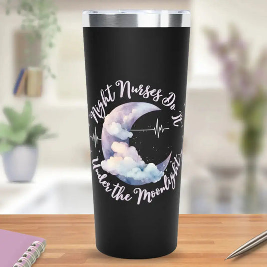 Black stainless steel tumbler with 'Night Nurses Do It Under the Moonlight' in white script, centered around a watercolor purple crescent moon with soft clouds and a heartbeat line design, on a blurred home background.