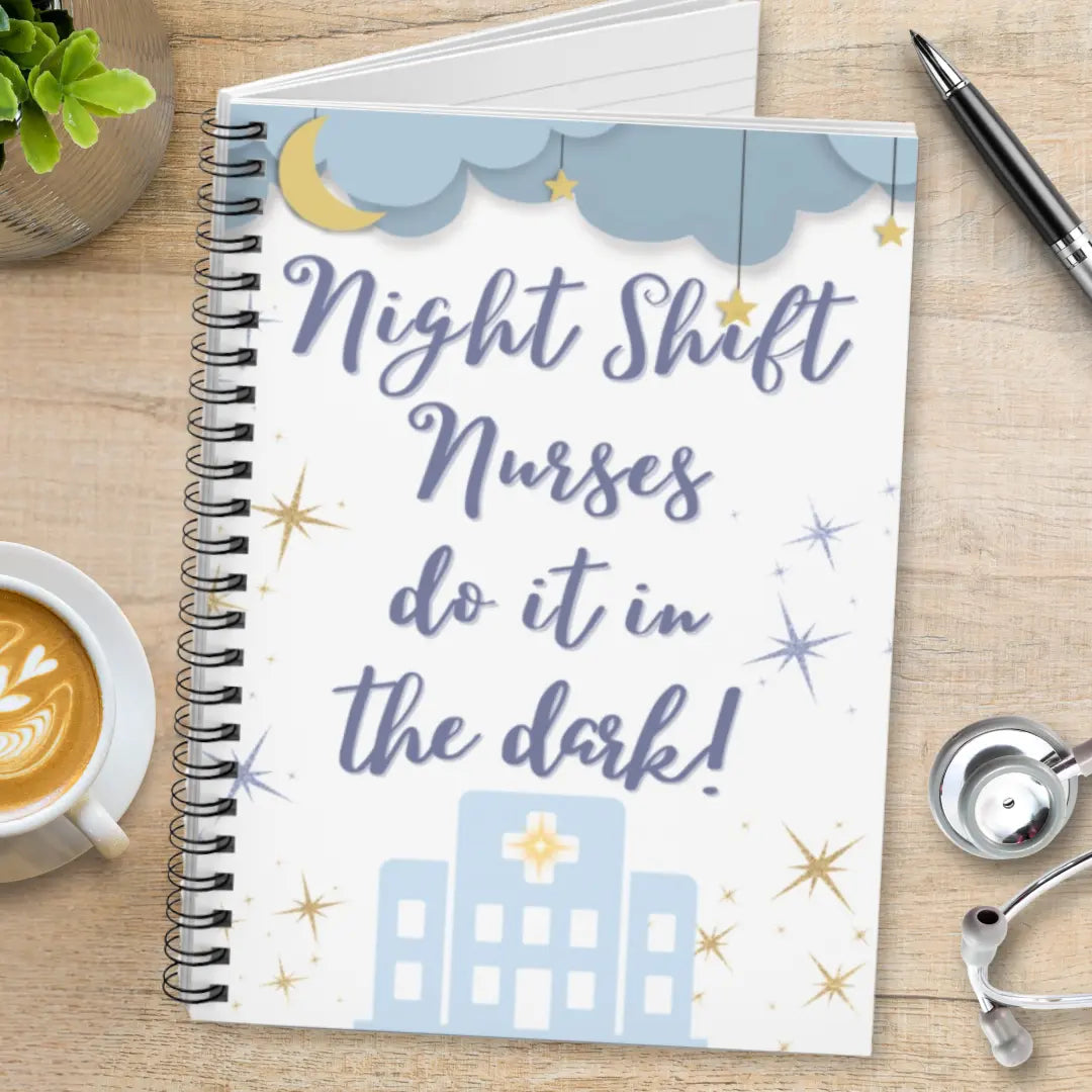 Notebook with 'Night Shift Nurses do it in the dark!' text on a wooden surface with a cup of coffee and stethoscope.