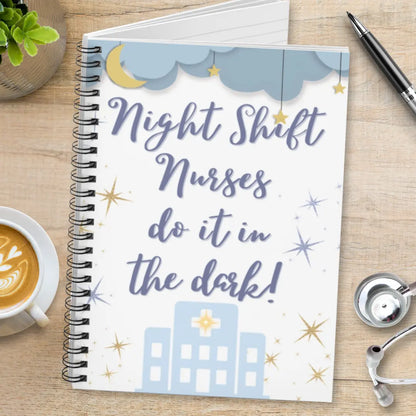 Notebook with 'Night Shift Nurses do it in the dark!' text on a wooden surface with a cup of coffee and stethoscope.