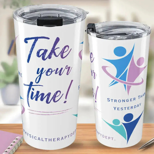 Two white stainless steel tumblers showing front and back views - front reads 'Take Your Time! #PhysicalTherapyDept.' in bold script, back reads 'Stronger Than Yesterday' with blue, pink, and teal movement figure graphics, on a wooden desk background.