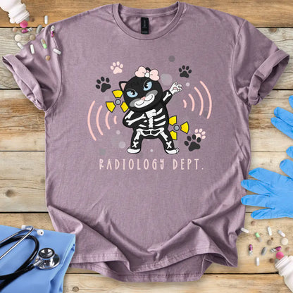 Pink t-shirt with a cartoon cat in a radiology-themed design on a wooden surface with medical accessories.
