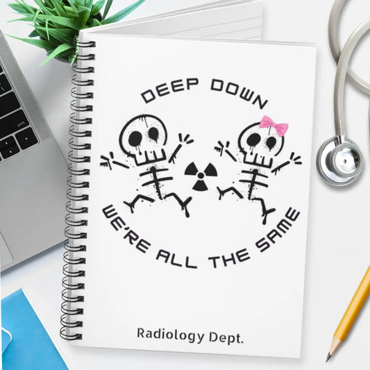 Notebook with skeleton design and 'Deep Down We're All The Same' text on a desk.