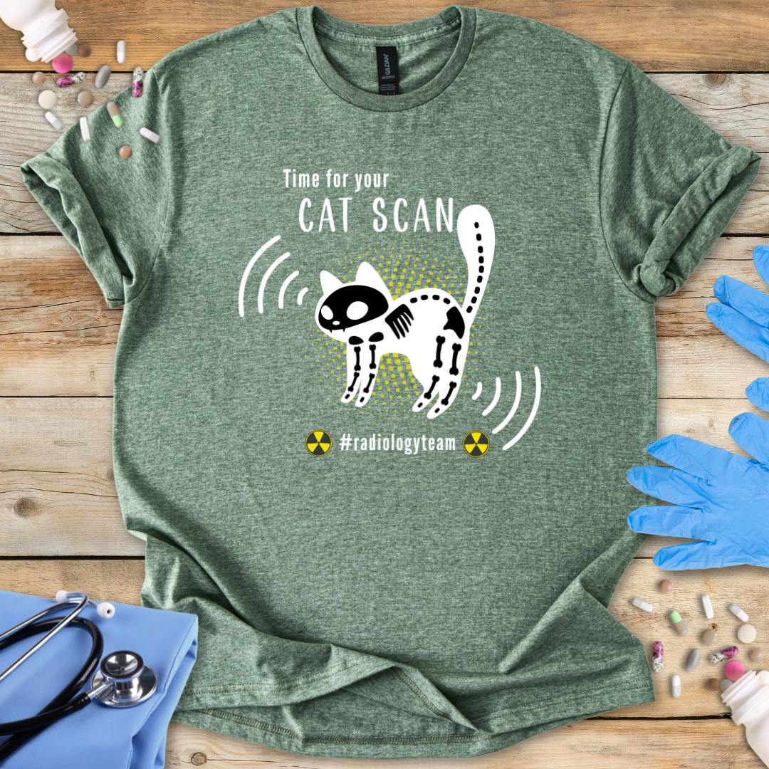 Green t-shirt with a cat scan graphic and text on a wooden surface with medical-themed items.