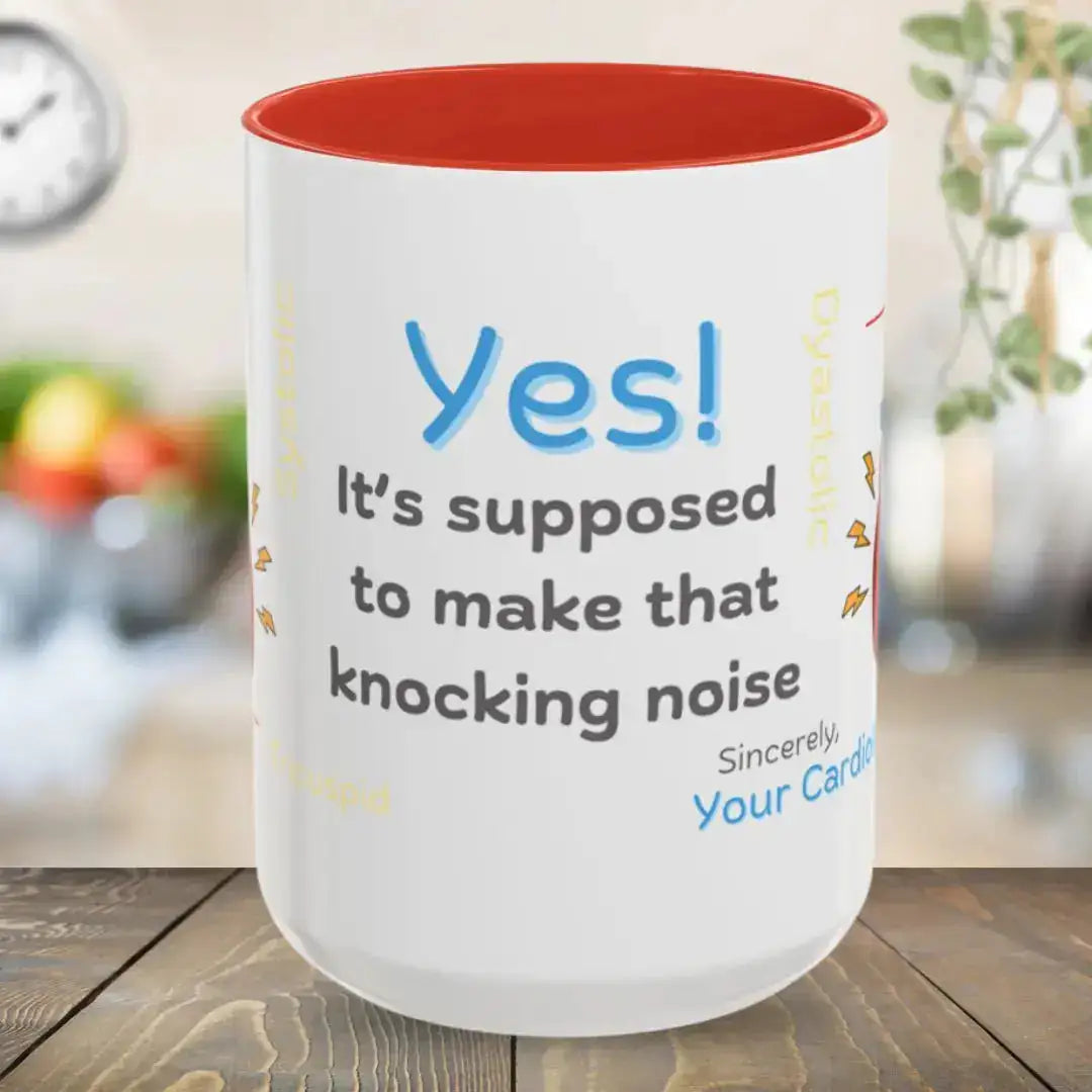 White mug with red interior and humorous text 'Yes, It's Supposed To Make That Knocking Noise' on a wooden surface