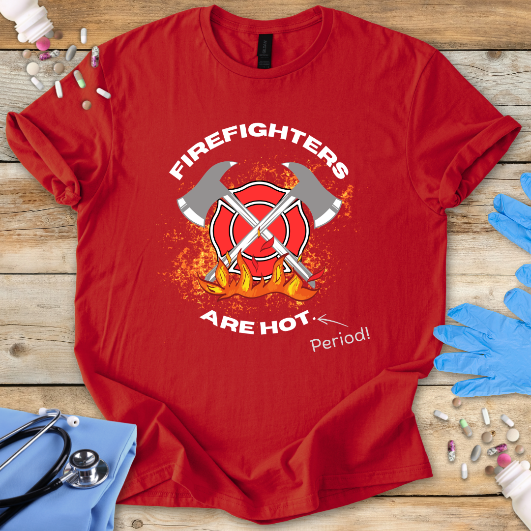 Red t-shirt with 'Firefighters Are Hot Period!' graphic on a wooden surface with medical supplies.