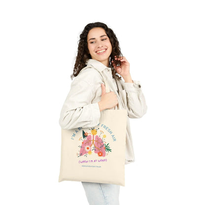 Woman holding a tote bag with floral design and text on a white background