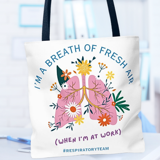 Tote bag with lungs and flowers design, text 'I'm a breath of fresh air (when I'm at work) #respiratoryteam' on a blurred medical background.
