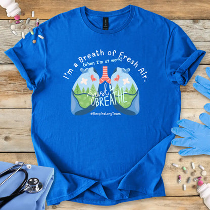 Royal Blue t-shirt with respiratory lungs graphic and 'I'm a breath of fresh air' text on a wooden surface with medical items.