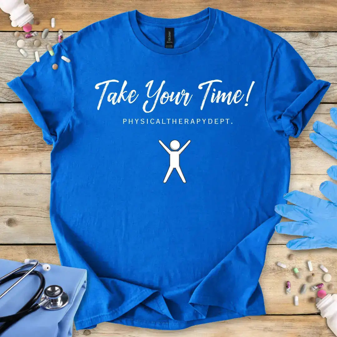 Blue t-shirt with 'Take Your Time! Physical Therapy Dept.' text and graphic on a wooden surface with medical items.