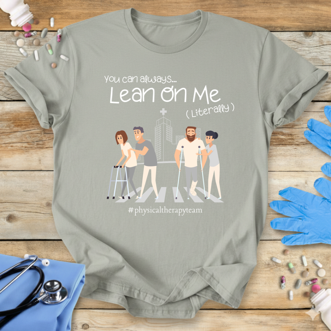 Sage med t-shirt with graphic design and 'Physical Therapy Team' text on a wooden surface with medical supplies.