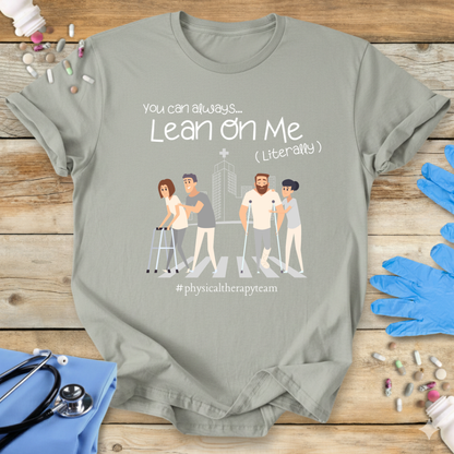 Sage med t-shirt with graphic design and 'Physical Therapy Team' text on a wooden surface with medical supplies.