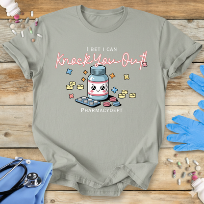 Sage med t-shirt with a pharmacy-themed graphic and 'I bet I can knock you out' text on a wooden surface with medical accessories.