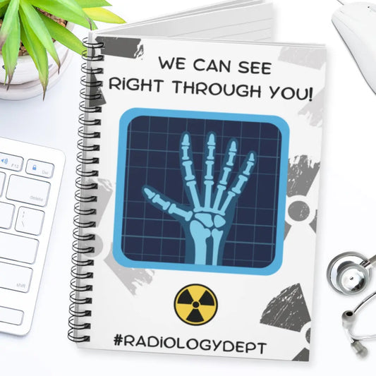 Notebook with x-ray design and 'We Can See Right Through You Radiology Dept' text on a white surface with medical-themed items.