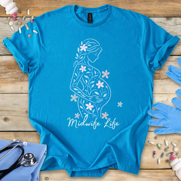 Blue t-shirt with 'Midwife Life' text on a wooden surface with medical supplies.