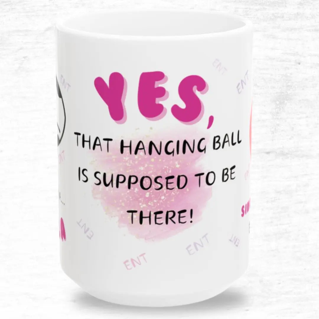 White mug with pink and black 'Yes that hanging ball is supposed to be there' text on a white background