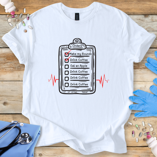 White t-shirt with a humorous doctor's checklist design on a wooden surface with medical-themed items.