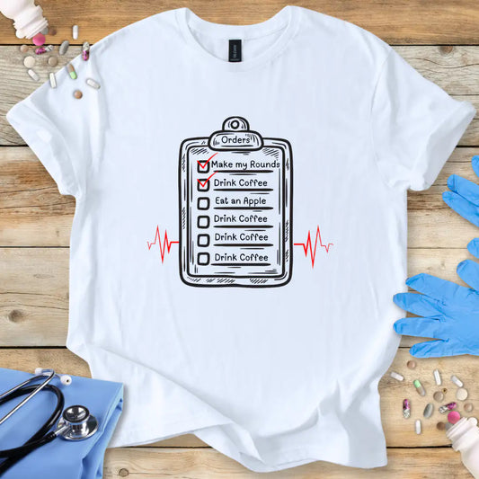 White t-shirt with a humorous doctor's checklist design on a wooden surface with medical-themed items.