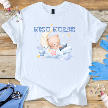 White t-shirt with NICU Nurse text  featuring a teddy bear and baby on a wooden surface with medical supplies.